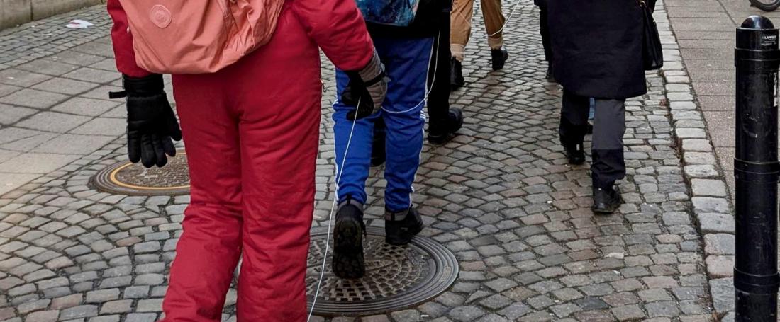 Personer går på en gata, och följer ett snöre utlagt på marken.